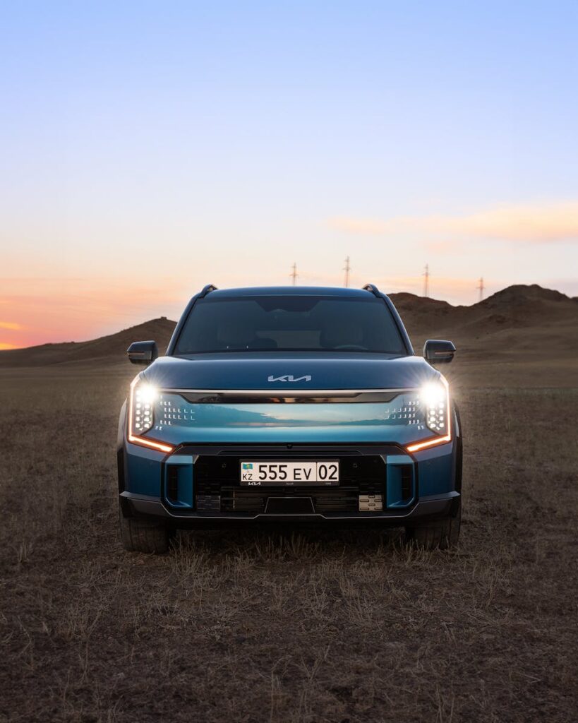 A sleek electric SUV parked on grasslands during sunset in Kazakhstan.