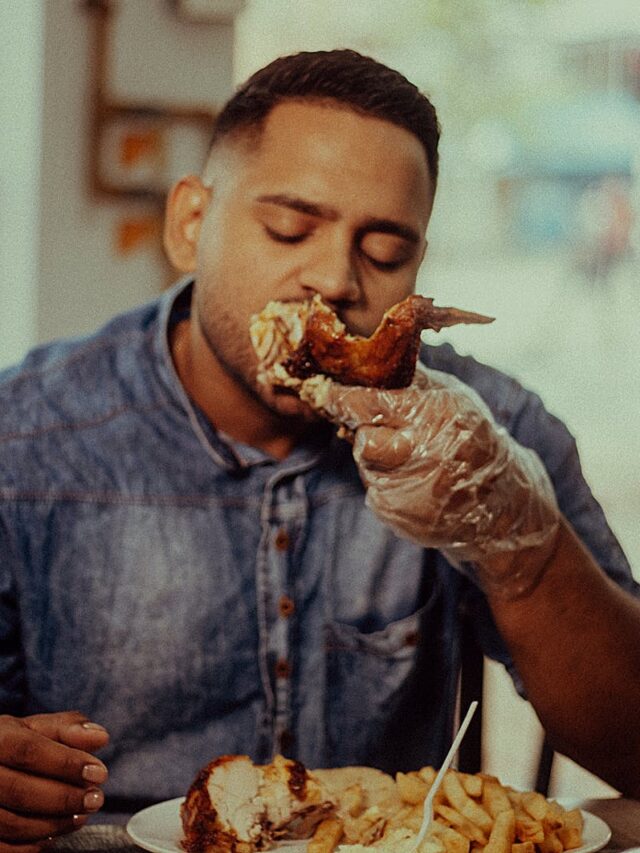 A man delightfully eats roasted chicken and fries in a cozy cafe in Perugia, Italy.