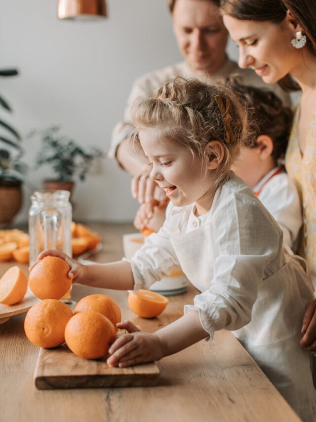 Joyful family with children making fresh orange juice in a bright kitchen setting.
